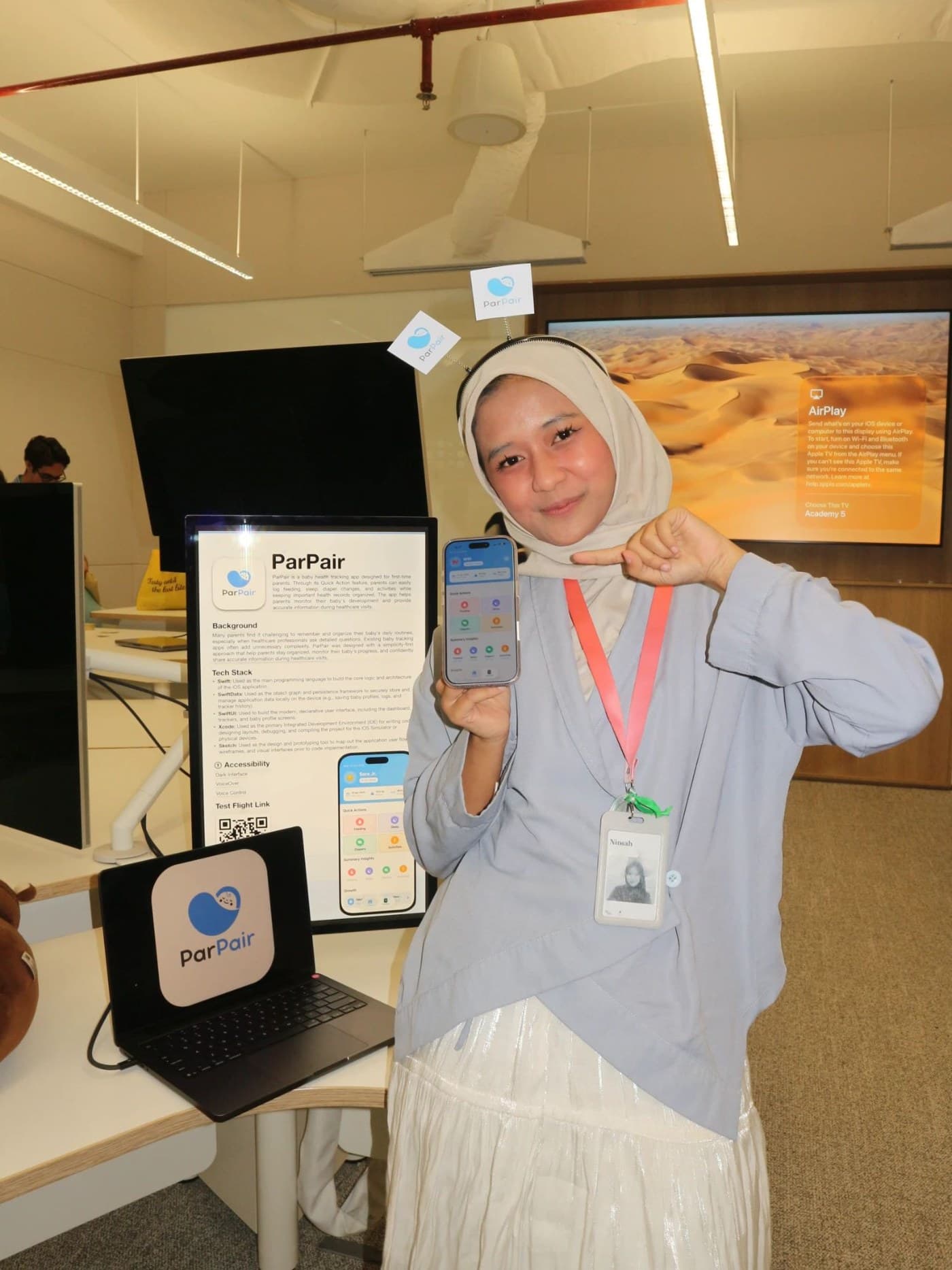 Ni'mah at the ParPair showcase booth: live app demo on iPhone, project poster with tech stack, and TestFlight QR